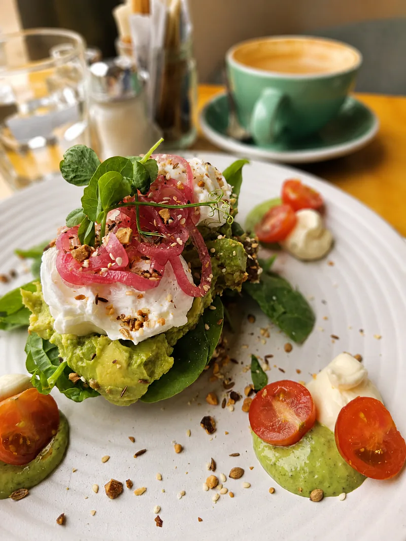 Avocado toast with poached egg, pickled onion and a green coffee cup at Yellow