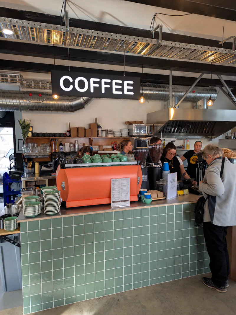 The orange coffee machine and green tiled counter inside Yellow