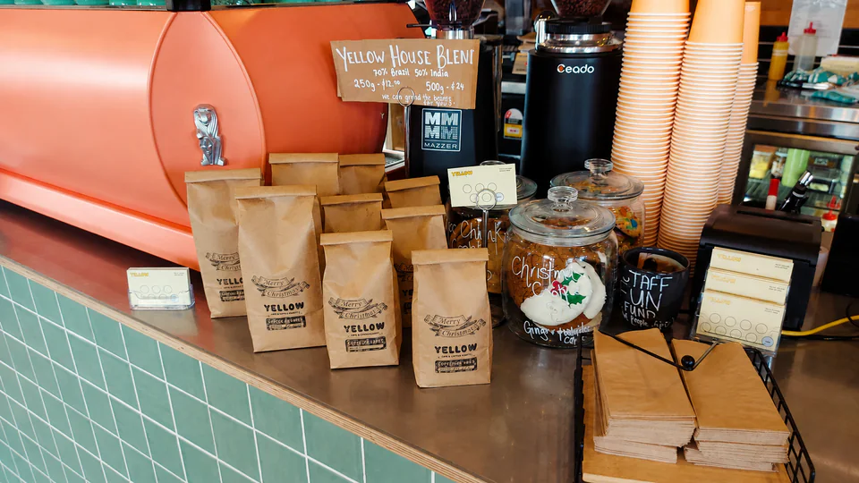 Yellow House Blend coffee bags and the handwritten blend sign at the counter