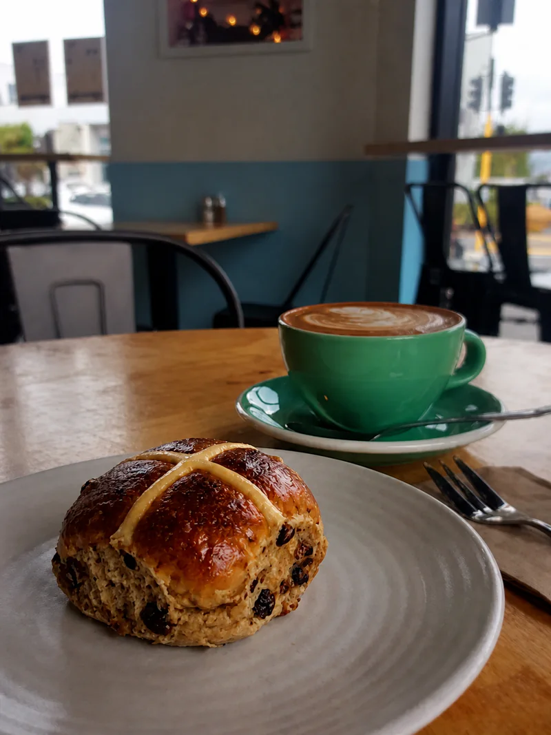 A sweet bun and a green cup of coffee on a table at Yellow